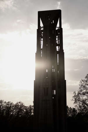 A tall building under a cloudy sky and sunlight surrounded by greeneryの写真素材