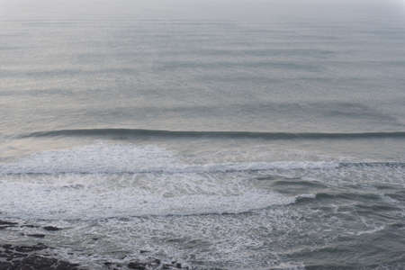 A closeup shot of calm ocean waves moving towards the shore during evening time