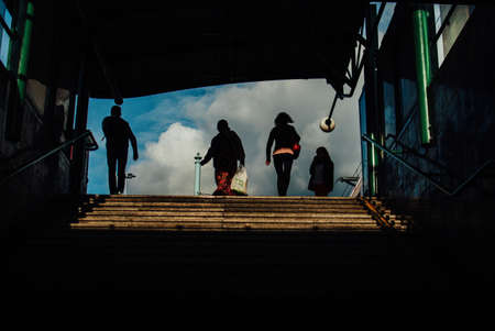 A group of people on top the stairs with the cloudy sky visible in the backgroundの写真素材