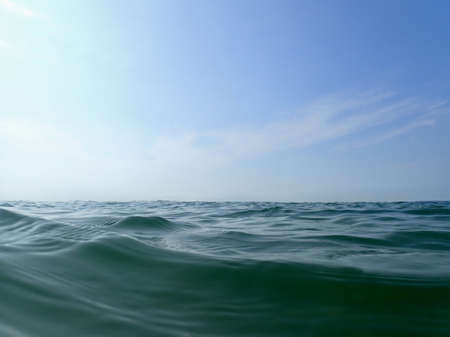A closeup look of the sea waves under a blue sky and sunlight - a cool picture for backgroundsの写真素材