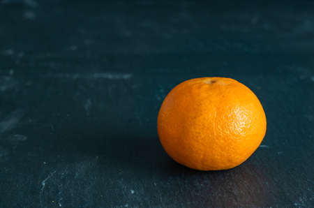 A high angle shot of a delicious tangerine on a dark blue surfaceの写真素材