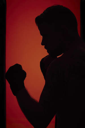 A silhouette of a person boxing against the wall with a red and orange backgroundの写真素材