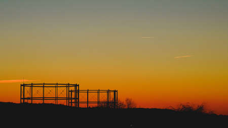 The silhouettes of trees and an iron contruction under the colorful sunset sky