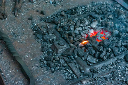 A high angle shot of burning coal in the blacksmith's workshop with a small flame in the center