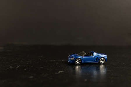 A selective focus shot of a blue toy sports car on a black surfaceの写真素材