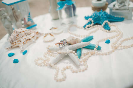A white and blue wedding decorations on a white table on a beach with the sea on the backgroundの写真素材