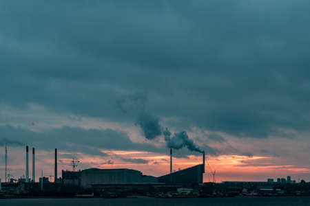 A beautiful view of a factory by the lake under the colorful skyの写真素材