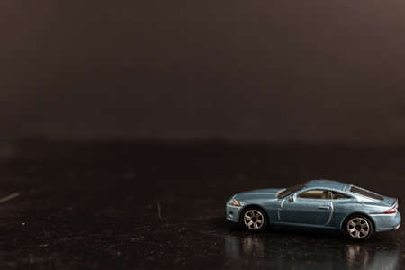 A selective focus shot of a light blue toy car on a black surfaceの写真素材