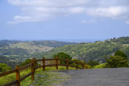 A road surrounded by wooden fences with hills covered in forests on the backgroundの写真素材