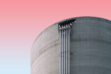 A low angle shot of a concrete building with pipes on a pink backgroundの写真素材
