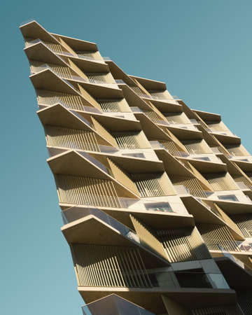 A vertical low angle shot of a beige metal building under the blue skyの写真素材