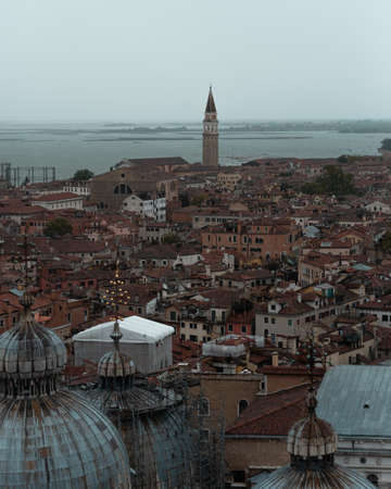 A vertical shot of city buildings near the sea under a cloudy skyの写真素材