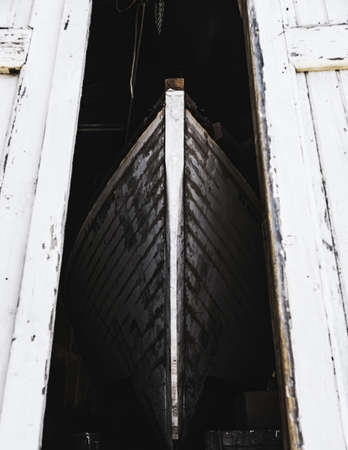 An old rusty ship in a building with white wooden doors under sunlightの写真素材