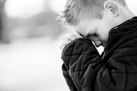 A boy standing with closed eyes and prayingの写真素材