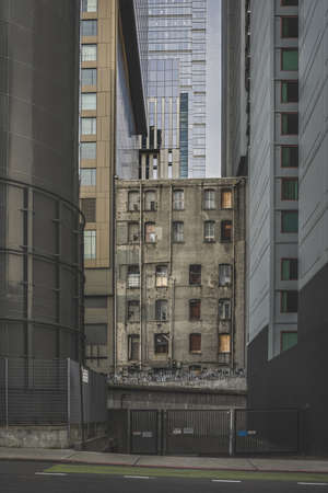 An old ruined building surrounded by modern skyscrapers with glass windows