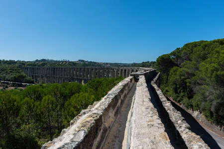 The Roman aqueduct of Pegoes surrounded by greenery under sunlight in Tomar in Portugalの写真素材