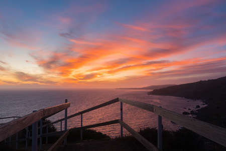 A breathtaking sunset over the calm ocean surrounded by hillsの写真素材