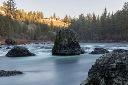 A beautiful scenery of rock formations in a river surrounded by fir trees