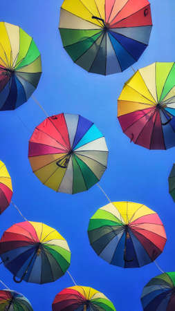 A vertical shot of colorful umbrellas under the clear skyの写真素材
