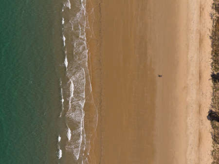 A high angle shot of a beach with a small town at the shore