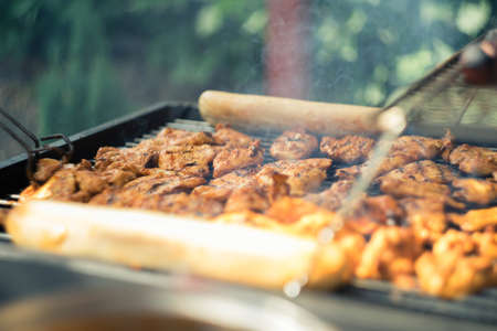 A lot of seasoned meat being barbecued on a grilling machineの写真素材