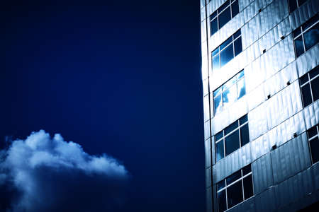 A low angle shot of a building touching the fluffy clouds in the skyの写真素材