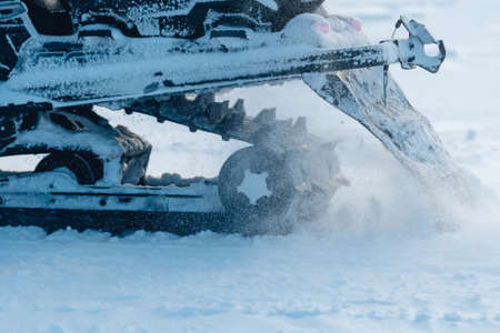 A closeup shot of the snowmobile wheels while splashing snow aroundの写真素材