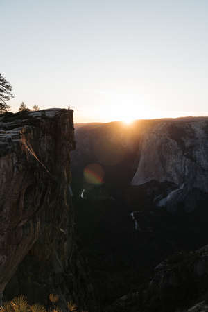 A breathtaking scenery of the sun rising over a rock formation covered in greenery