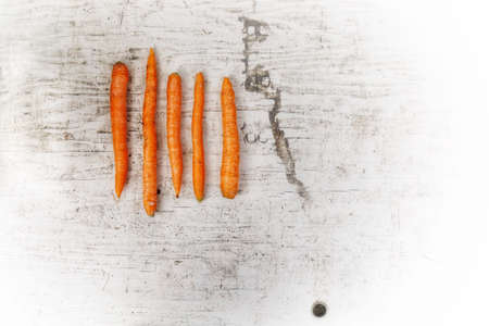 PORTLAND, UNITED STATES - Nov 23, 2019: A high angle shot of five carrots with different size and shapes on a white surfaceの写真素材
