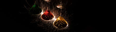 A panoramic shot of upside-down colorful cocktails with sparks on a black background