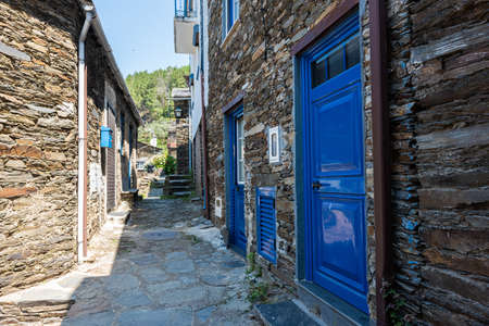 An alley surrounded by buildings with colorful doors under sunlight in Piodao village in Portugalの写真素材