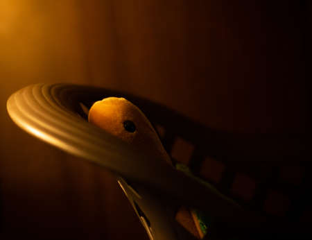 A selective focus shot of a yellow Dimly lit stuffed turtle in a chairの写真素材