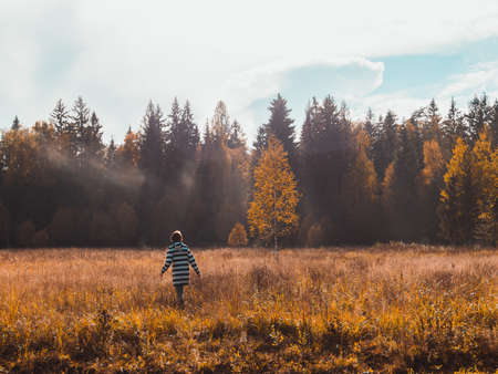 The child walking in the valley with dry grass near the forest - childhood in the countryside conceptの写真素材