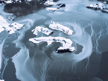 A birds-eye view of the frozen pieces of ice in the middle of the frosty blue lake in Iceland