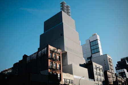 A low angle shot of an apartment near a tall building with a blue sky in the background