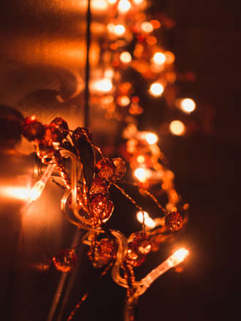 A closeup of orange lights and decorations against a wall with a blurry background and a bokeh effectの写真素材