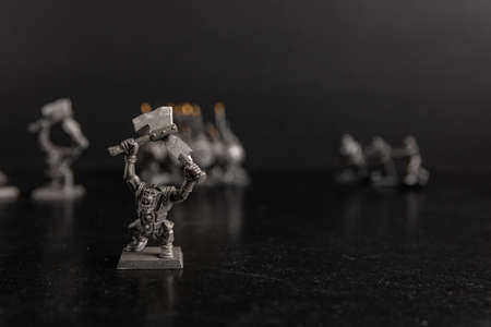 A grayscale selective focus shot of a creature holding axes figurineの写真素材