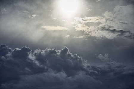 A beautiful scenery of white puffy clouds under bright sun raysの写真素材