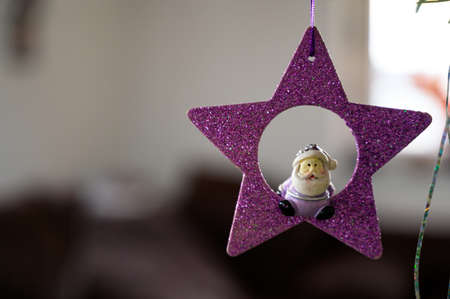 A selective focus shot of a Christmas star-shaped purple ornament with the small Santa sitting on itの写真素材