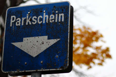 A blue traffic sign in Munich with colorful trees on the blurry background in Germanyの写真素材