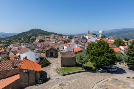 A high angle view of the Belmonte surrounded by hills covered in greenery under sunlight in Portugalのeditorial素材