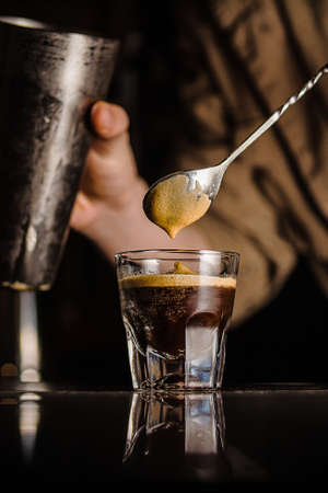 A vertical closeup shot of a person stirring the coffee in a small glassの写真素材