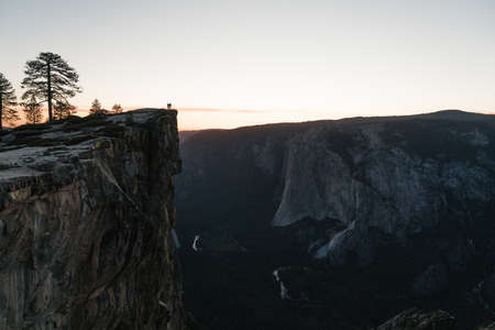 A scenery of people standing on top of a rock formation admiring the beauty of natureの写真素材