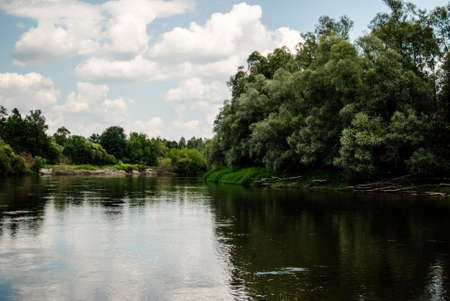 The reflection of the beautiful trees and the blue sky in the riverの写真素材