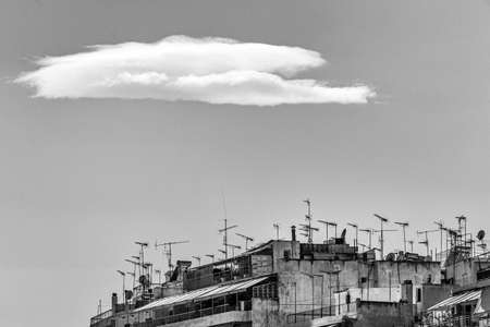 A low angle grey scale shot of buildings underneath the clouds in the skyの写真素材