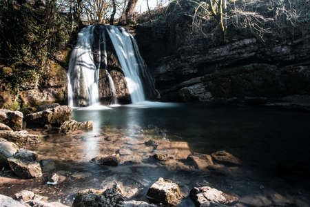 A waterfall flowing splashing to the rocks in the middle of a forest