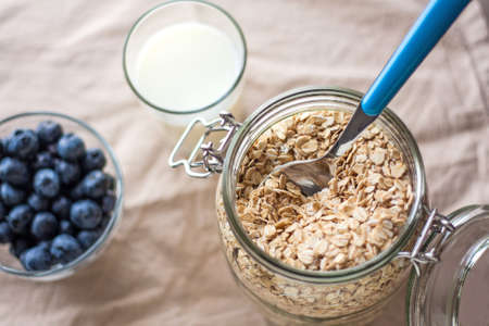 A high angle shot of a cup of blueberries and oatmeal on a white table cloth