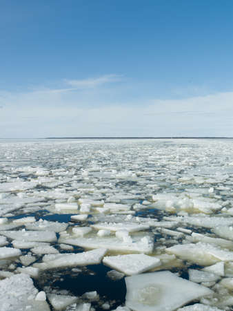 A vertical shot of the pieces of ice in the frozen lake under the bright sky in winter