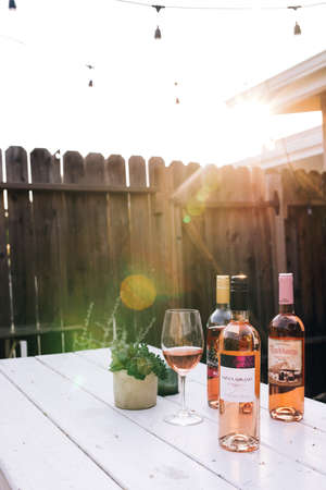 SAN CLEMENTE, UNITED STATES - Dec 20, 2018: A vertical image in a backyard patio during the golden hour of wine bottles on a picnic table with rose wine.のeditorial素材
