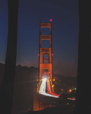 A vertical timelapse shot of the golden gate bridge with cars driving at night time